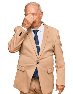 Senior caucasian man wearing business suit and tie tired rubbing nose and eyes feeling fatigue and headache. stress and frustration concept.