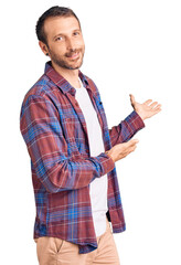 Young handsome man wearing casual clothes inviting to enter smiling natural with open hand