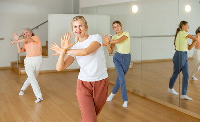 Smiling female doing dance workout during group classe in fitness center
