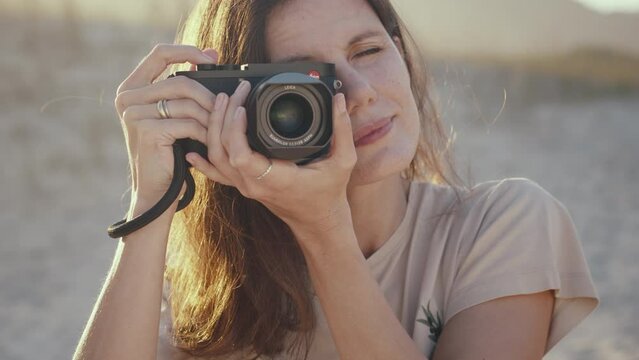 Female photographer. Woman photographer takes pictures outdoor with mirrorless camera