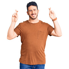 Young hispanic man wearing casual clothes gesturing finger crossed smiling with hope and eyes closed. luck and superstitious concept.