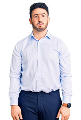 Young hispanic man wearing business clothes puffing cheeks with funny face. mouth inflated with air, crazy expression.