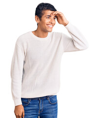 Fototapeta premium Young african amercian man wearing casual clothes very happy and smiling looking far away with hand over head. searching concept.