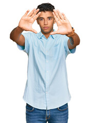 Fototapeta premium Young handsome african american man wearing casual clothes doing frame using hands palms and fingers, camera perspective