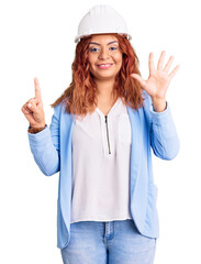 Young latin woman wearing architect hardhat showing and pointing up with fingers number six while smiling confident and happy.