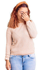 Young latin woman wearing casual clothes and diadem tired rubbing nose and eyes feeling fatigue and headache. stress and frustration concept.