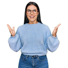 Young hispanic woman wearing casual clothes and glasses celebrating mad and crazy for success with...