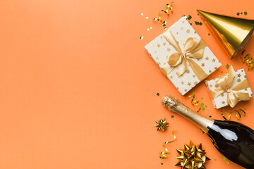 Flat lay composition of Champagne bottle gift box ribbons and confetti on colored background. Flat lay, top view holiday concept