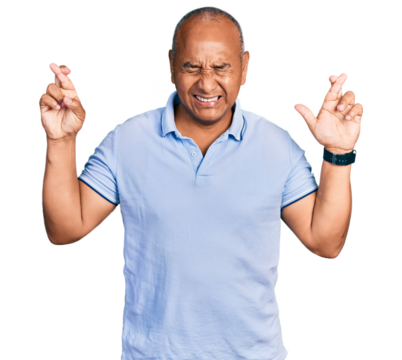 Hispanic middle age man wearing casual t shirt gesturing finger crossed smiling with hope and eyes closed. luck and superstitious concept.