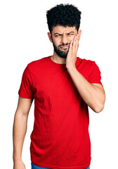 Young arab man with beard wearing casual red t shirt touching mouth with hand with painful expression because of toothache or dental illness on teeth. dentist