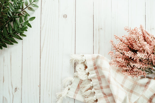 Pretty Pink And Green Themed Flatlay, Top Down View, With Pink Dried Flowers, Green Leaves And A Plaid Towel, On White Wood Background