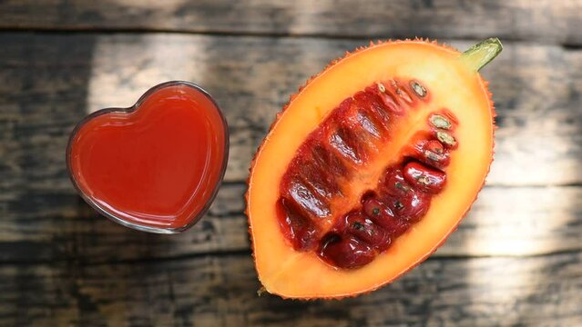 Gac fruits and juice on sunset light on old wood background.top view.