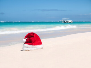 Fototapeta na wymiar Santa Claus Hat on sandy beach. Tropical New year celebration