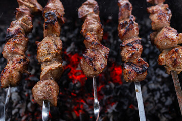 Close-up of skewered meat (shashlyk or Shish kebab) on the barbecue grill over charcoal - 539866730