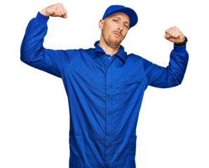 Bald man with beard wearing builder jumpsuit uniform showing arms muscles smiling proud. fitness concept.