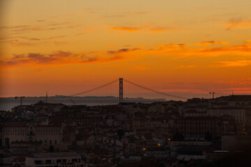 Lisbon city old town landscape during sunset. Golden hour in Lisbon with a view of red rooftops, blue sky and the April 25 Bridge in a distance, view of Lisbon from S&atilde;o Jorge Castle