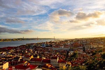Lisbon city old town landscape during sunset. Golden hour in Lisbon with a view of red rooftops, blue sky and the April 25 Bridge in a distance, view of Lisbon from S&atilde;o Jorge Castle