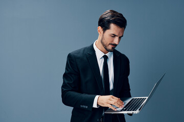 Business man looking at the laptop screen on a blue background in a business suit