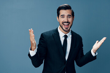 A man of business smiles with his hands up and points to an empty space to copy on a blue background