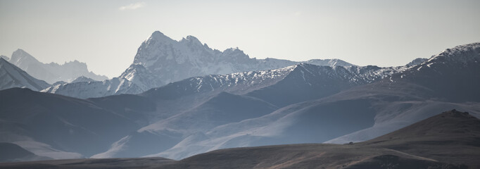 Mountain rocky ranges of the Caucasus with snow and glaciers, panorama on a sunny summer morning