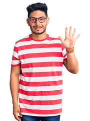 Handsome latin american young man wearing casual clothes and glasses showing and pointing up with fingers number four while smiling confident and happy.