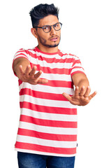Handsome latin american young man wearing casual clothes and glasses doing stop gesture with hands palms, angry and frustration expression