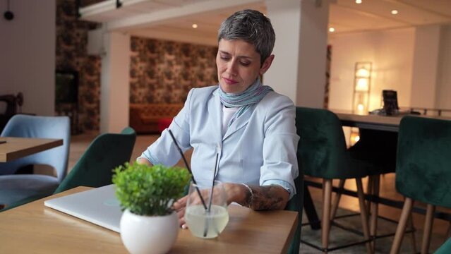 One woman stretching while sit at cafe at the table with laptop computer taking a brake stretching arms and back sore neck pain relief business yoga concept real people candid video