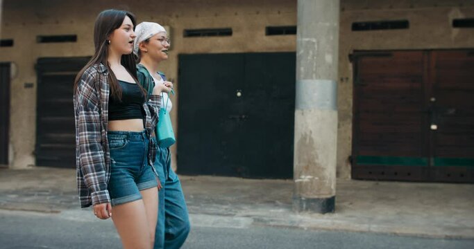 A group of girls meet in neighborhood garages in the city to perform a dueling dance. Teenagers holding portable music speakers high-five each other.