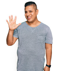 Young latin man wearing casual clothes showing and pointing up with fingers number five while smiling confident and happy.