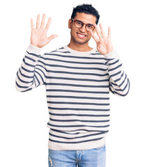 Hispanic handsome young man wearing casual clothes and glasses showing and pointing up with fingers number nine while smiling confident and happy.