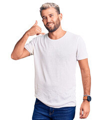 Young handsome blond man wearing casual t-shirt doing happy thumbs up gesture with hand. approving expression looking at the camera showing success.