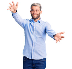 Young handsome blond man wearing elegant shirt looking at the camera smiling with open arms for hug. cheerful expression embracing happiness.