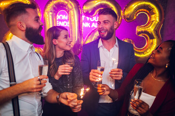 Multiracial friends celebrating new years eve with champagne and sparklers