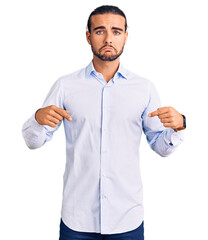 Young handsome man wearing business clothes pointing down looking sad and upset, indicating...