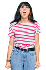 Obraz premium Young hispanic girl wearing casual clothes angry and mad screaming frustrated and furious, shouting with anger. rage and aggressive concept.