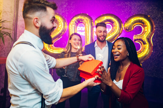 Multiracial couple exchanging gifts for birthday party or new years eve in the club