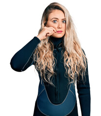 Young blonde woman wearing diver neoprene uniform mouth and lips shut as zip with fingers. secret...