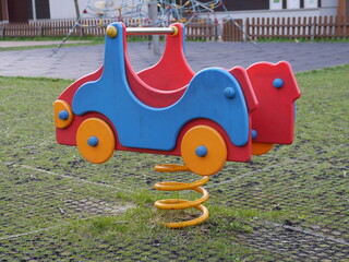 Colorful swing in shape of a car for children in playground.