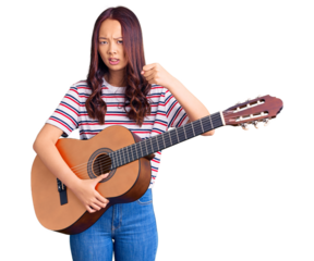 Young beautiful chinese girl playing classical guitar annoyed and frustrated shouting with anger, yelling crazy with anger and hand raised