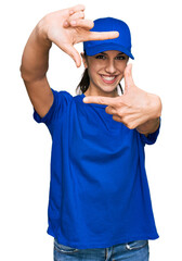 Young hispanic girl wearing delivery courier uniform smiling making frame with hands and fingers with happy face. creativity and photography concept.