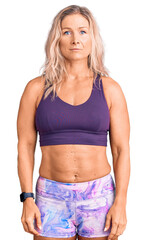 Middle age fit blonde woman wearing sportswear with serious expression on face. simple and natural looking at the camera.