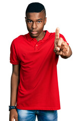 Young african american man wearing casual red t shirt pointing with finger up and angry expression, showing no gesture