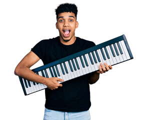 Young african american man holding piano keyboard celebrating crazy and amazed for success with...