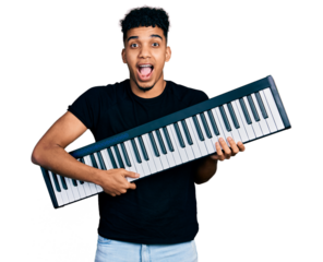 Young african american man holding piano keyboard celebrating crazy and amazed for success with open eyes screaming excited.