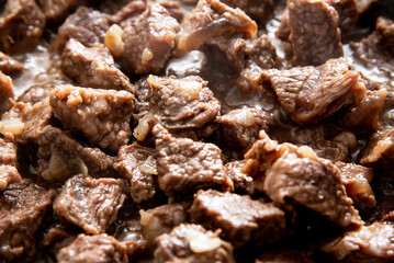 close-up beautiful large pieces of fried meat with onions in a pan