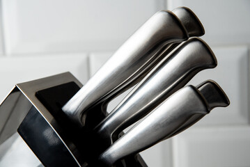 a set of 5 kitchen knives in a stand stands on the table, close-up