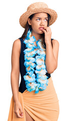 Young beautiful latin girl wearing hawaiian lei and summer hat looking stressed and nervous with...