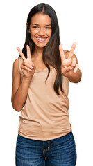 Beautiful hispanic woman wearing casual clothes smiling looking to the camera showing fingers doing victory sign. number two.