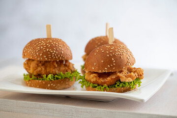 mini burgers with cheese and lettuce with sticks on a wooden background 