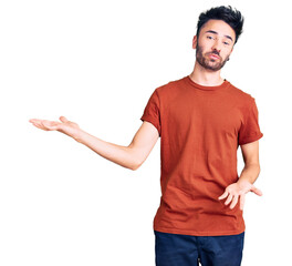 Young hispanic man wearing casual clothes clueless and confused expression with arms and hands raised. doubt concept.